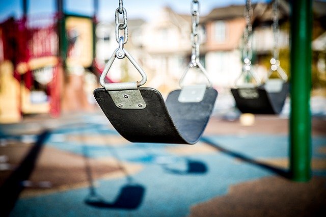 swing with playground equipment in background