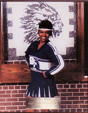 A woman posing in a cheerleading outfit.
