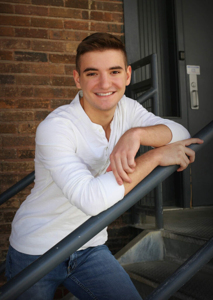 high school male posing for a senior photo in a white shirt