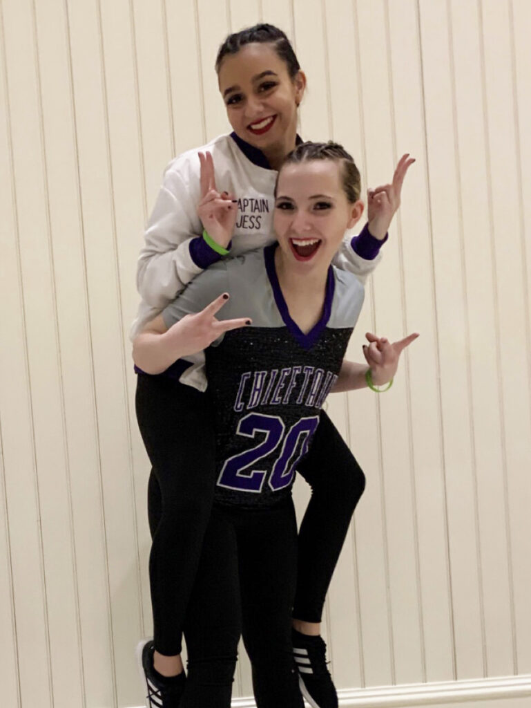 two female high school students smiling while displaying peace signs with their hands