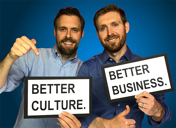 Two men with beards and blue shirts holding signs.